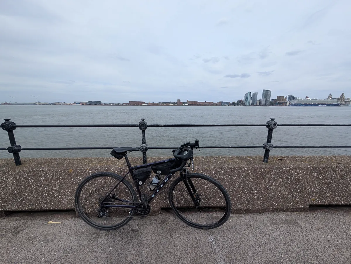 A bike against riverside railings with a city skyline across the water