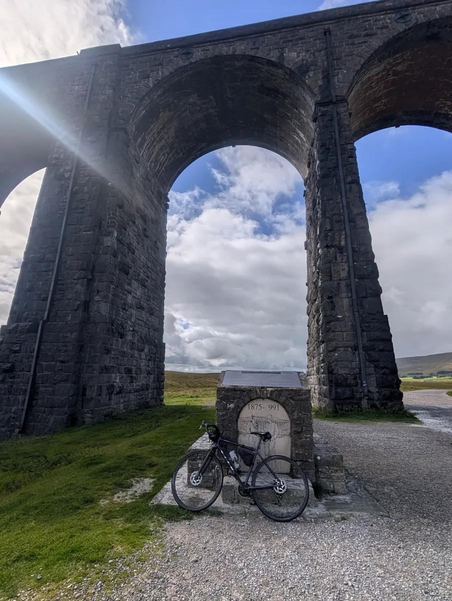 A bike beneath the arches of a stone railway viaduct